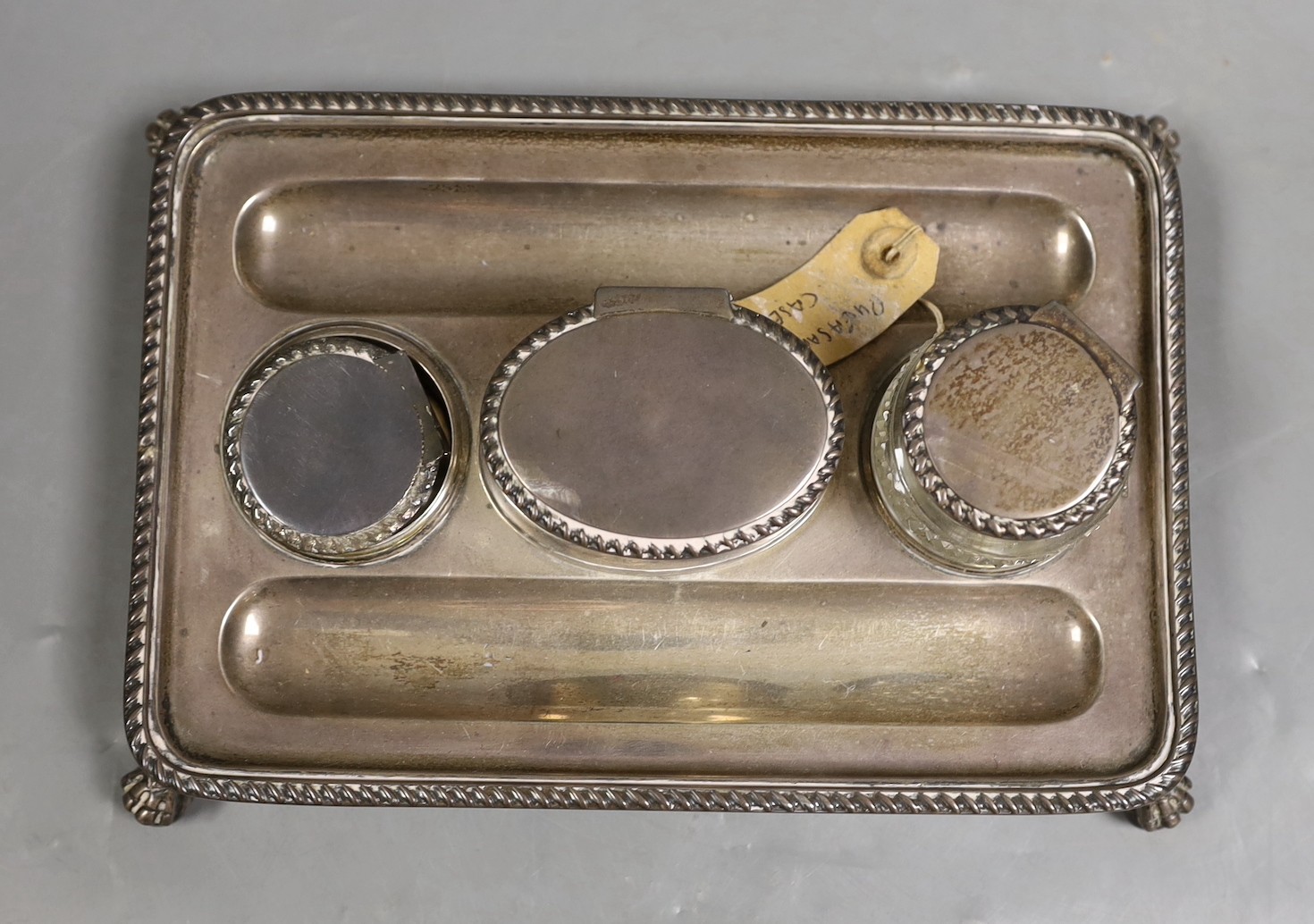A late Victorian silver rectangular inkstand, with two wells and central lidded compartment, (glass well missing), on claw and ball feet, John Grinsell & Sons, London, 1895, 20.4cm, 12.9oz.